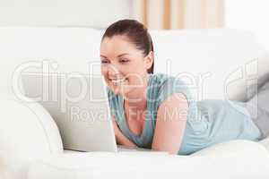 Attractive woman relaxing with her laptop while lying on a sofa