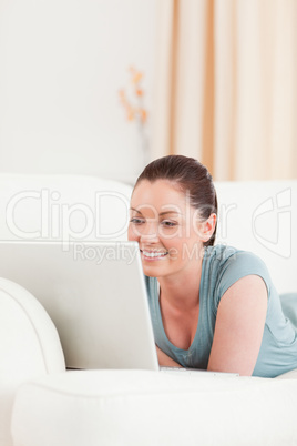 Charming woman relaxing with her laptop while lying on a sofa