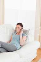 Good looking woman on the phone while lying on a sofa