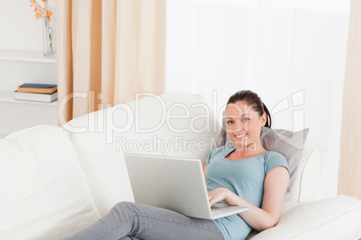 Pretty woman relaxing with her laptop while lying on a sofa