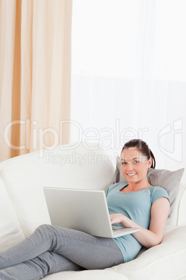 Gorgeous woman relaxing with her laptop while lying on a sofa