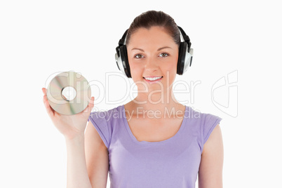Good looking woman with headphones holding a CD while standing