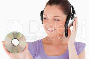Beautiful woman with headphones holding a CD while standing