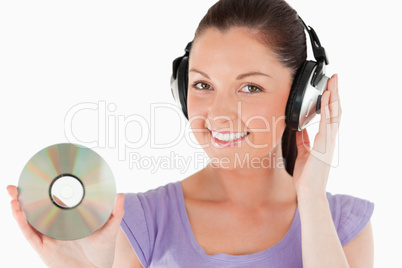 Attractive woman with headphones holding a CD while standing