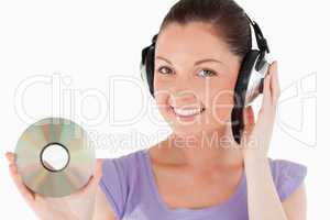 Attractive woman with headphones holding a CD while standing