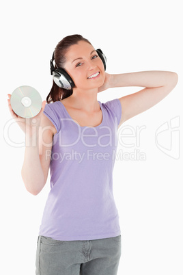 Pretty woman with headphones holding a CD while standing