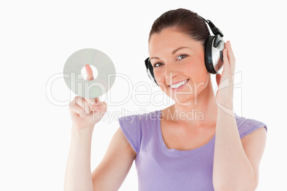 Cute woman with headphones holding a CD while standing