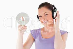 Cute woman with headphones holding a CD while standing