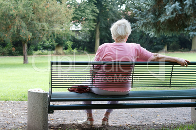 Seniorin sitz auf eine Bank im Park