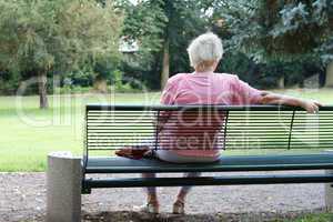 Seniorin sitz auf eine Bank im Park