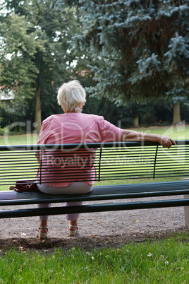 Seniorin sitz auf eine Bank im Park