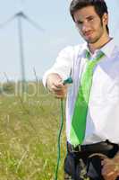 Green energy businessman in field hold plug