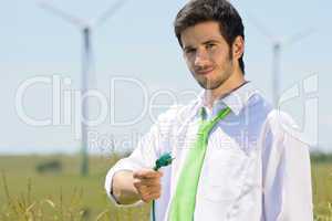 Green energy businessman in field hold plug