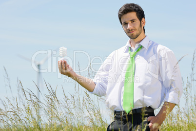 Green energy businessman in field hold bulb
