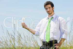 Green energy businessman in field hold bulb