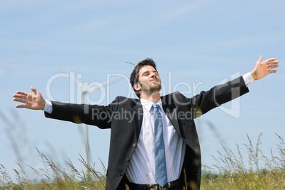 Green energy - Young businessman in field windmill