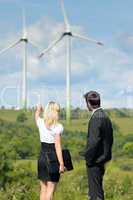 Green energy businesspeople in field show windmill