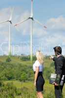 Green energy businesspeople in field show windmill