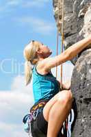 Rock climbing blond woman on rope sunny