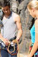 Rock climbing man showing woman rope knot