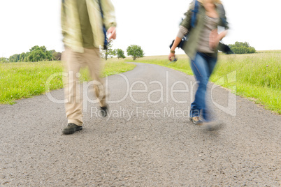 Hiking couple legs backpack on asphalt road