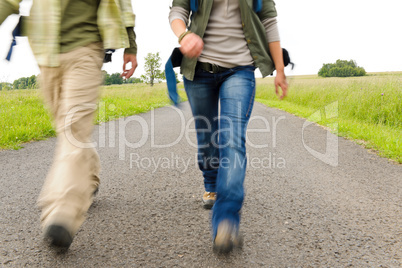 Hiking couple legs backpack on asphalt road