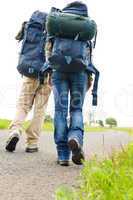 Hiking couple legs backpack on asphalt road