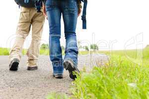 Hiking couple legs backpack on asphalt road