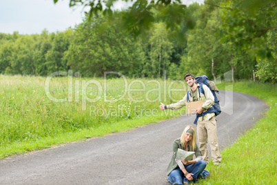 Hitch-hiking young couple backpack asphalt road