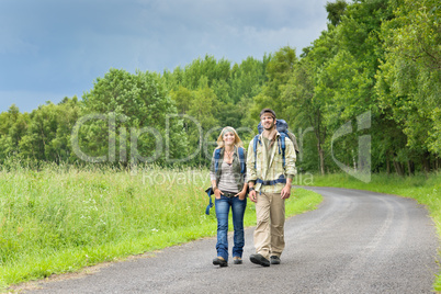 Hiking young couple backpack asphalt road countryside