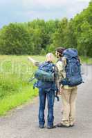 Hiking young couple backpack asphalt road countryside