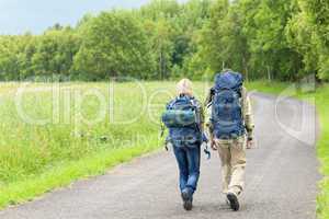 Hiking young couple backpack asphalt road countryside
