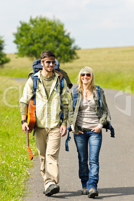 Hiking young couple backpack tramping asphalt road