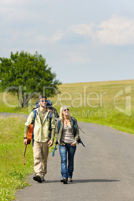 Hiking young couple backpack tramping asphalt road