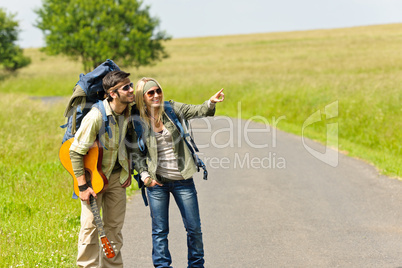 Hiking young couple backpack tramping asphalt road