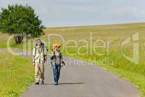 Hiking young couple backpack tramping asphalt road