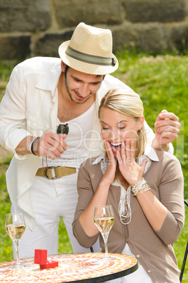 Surprised woman receiving wedding ring sunny terrace
