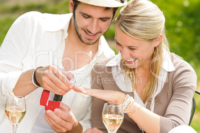 Cheerful woman receiving wedding ring sunny terrace