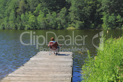 Elderly woman fishing from the dock.