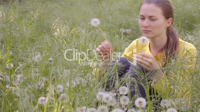 Young woman plucking dandelions on meadow