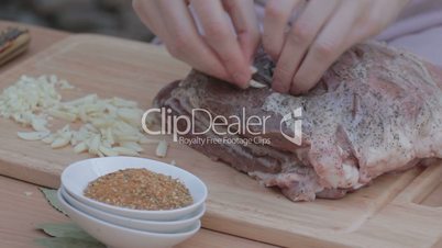 Tucking thin slices of garlic in salted and peppered pork