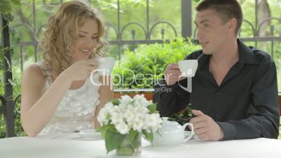 Romantic young couple having pleasant conversation at summer cafe