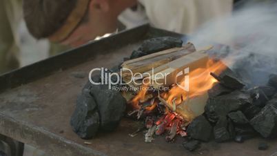 Adding black coal to fire done from paper and wood