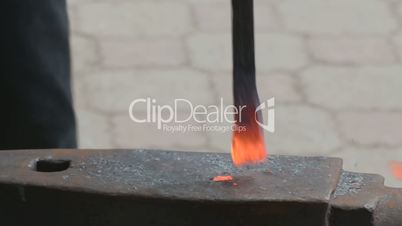 Blacksmith hammering hot metal rod to shape it