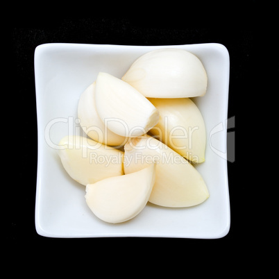 Garlic in a glass white plate on black background