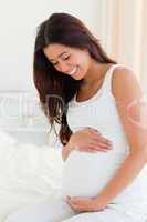 Portrait of an attractive pregnant woman touching her belly whil