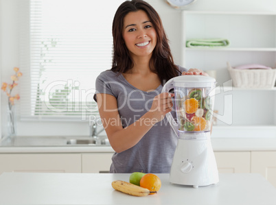 Attractive woman using a blender while standing