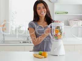 Attractive woman using a blender while standing