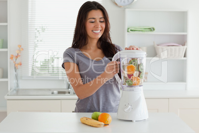 Charming woman using a blender while standing