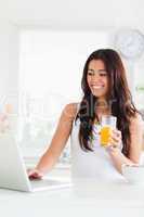 Gorgeous woman relaxing with her laptop while holding a glass of